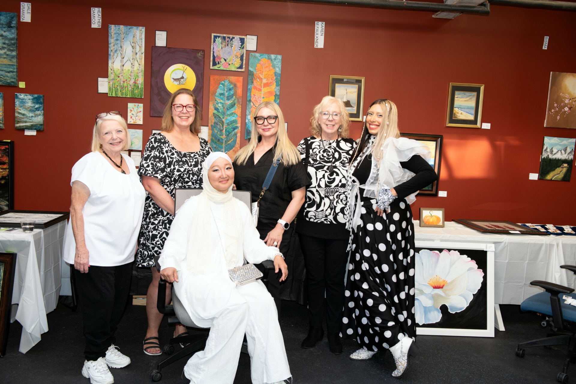 Tan with artists at a gallery exhibition surrounded by paintings