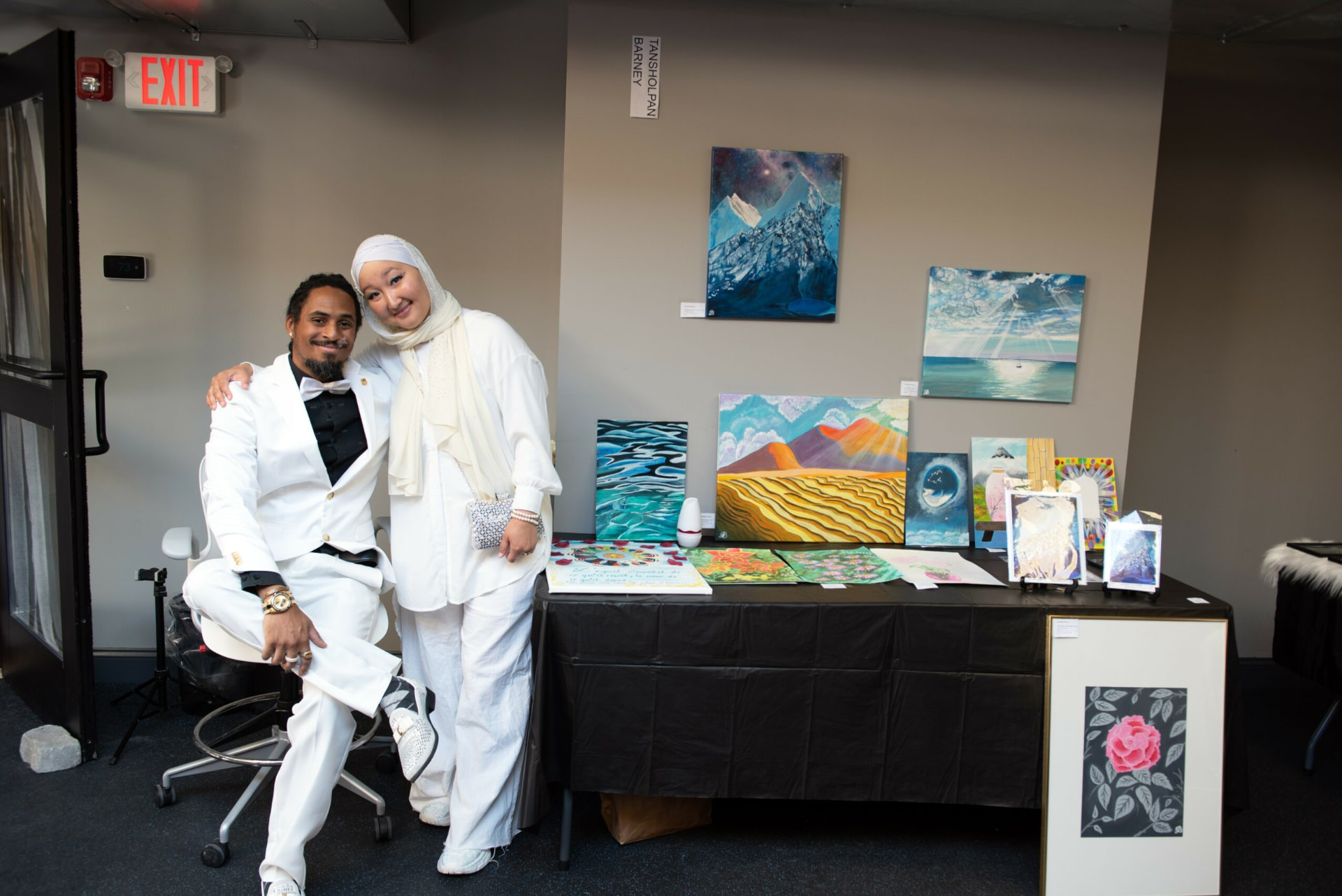 Tan beside a display of her paintings and artwork
