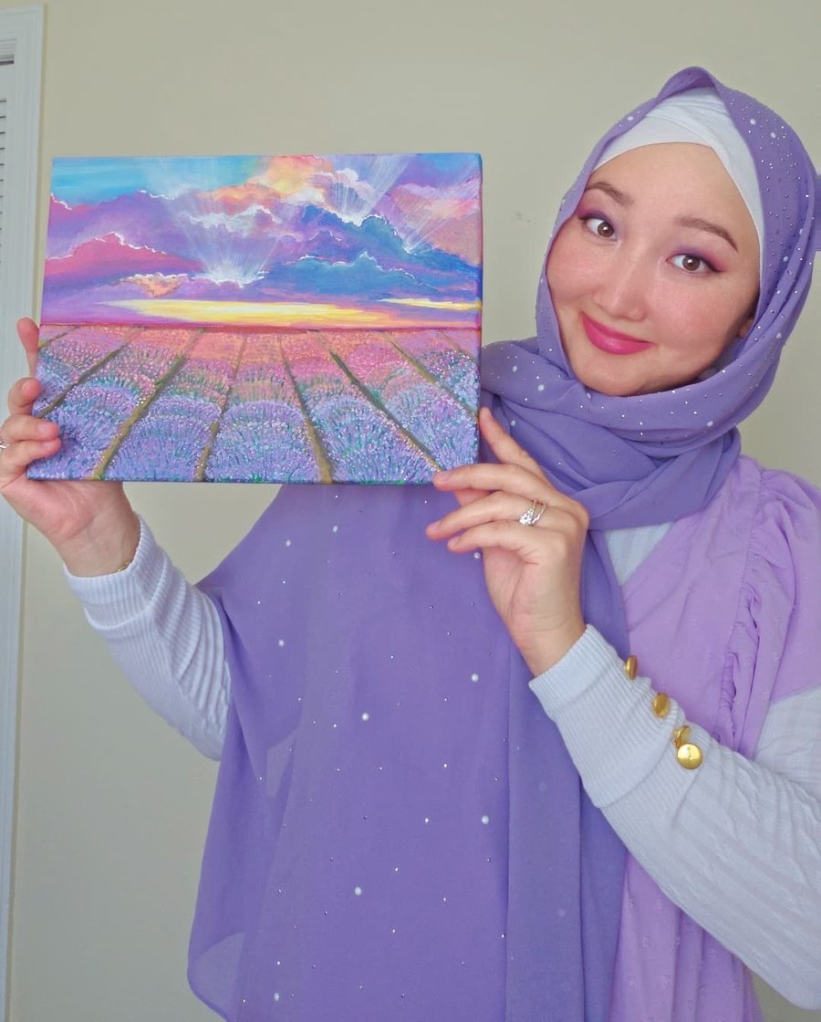Tan holding one of her lavender field paintings