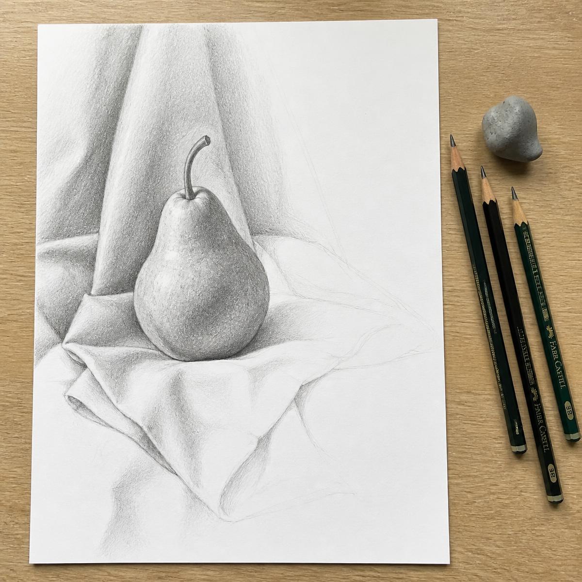 A student's graphite still-life drawing of a pear with pencils beside it